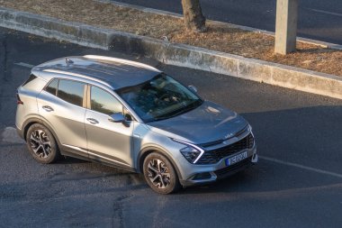 Günışığı altında asfalt yola park edilmiş modern gümüş rengi kia spor SUv, parlak tasarımını ve çağdaş özelliklerini sergiliyor.