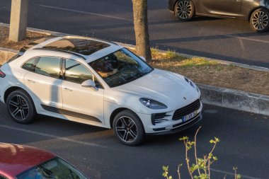 Yolun kenarına park etmiş beyaz Porsche Makan, altın saatin sıcak ışığını yansıtıyor.