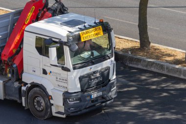 Yolun kenarına park etmiş beyaz adam kamyonu ön camında olağanüstü bir nakliye levhası taşıyor.