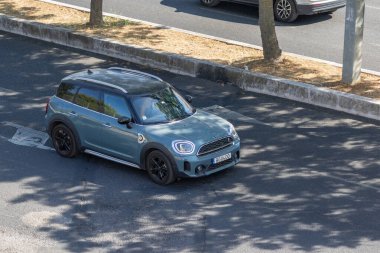 Açık mavi küçük bir vatandaş yaz güneşinin altında asfalt bir yolda gidiyor.