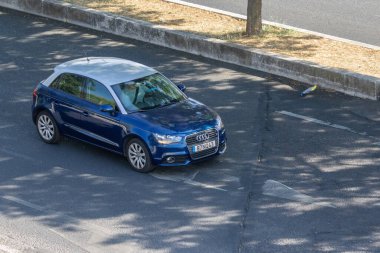 Şehir ortamında asfalt yolda modern mavi audi a1 sürüyor