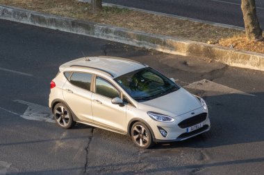 Modern beyaz Ford Fiesta Aktif araba gün batımında asfalt yolda dönüyor