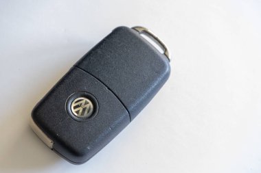İyi kullanılmış bir Volkswagen araba anahtarını beyaz arka planda dinlendirip, yıpranmış durumunun altını çizerek kapat