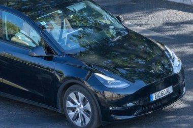 Güneşli bir günde Tesla modeli elektrikli araba kullanan bir iş adamı.