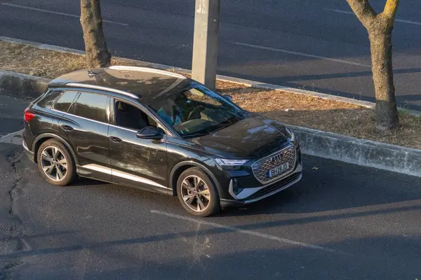 Parlak siyah Audi Q4 spor arabası yol kenarına park etmiş, modern tasarım ve elektrik yeteneklerini sergiliyor.