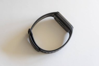 Beyaz bir yüzeyde dinlenen siyah akıllı saat sensörlerini ve minimalist tasarımını gösteriyor.