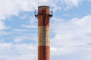 Paslı endüstriyel baca yükseliyor mavi gökyüzü ve beyaz bulutlara karşı