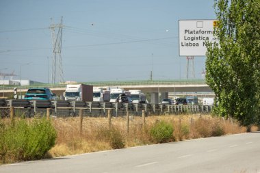 Otoyolda giden kamyonlar güneşli bir yaz gününde Portekiz 'deki Lizbon Kuzey Lojistik Platformu' na giriyor.