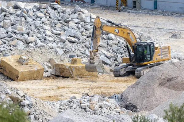 Bir yıkım alanındaki beton bloğu kaldıran kazıcı, geri dönüşüm malzemeleri