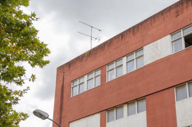Old damaged building with a television antenna and a street lamp on a cloudy day