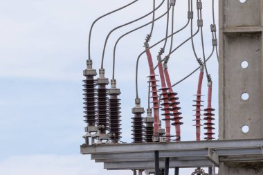Power lines with ceramic and polymer insulators distributing electricity on a cloudy day