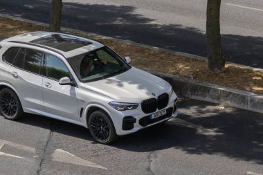 White bmw x5 suv driving on an asphalt road under natural light