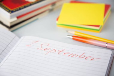 Üzerinde yazı olan açık bir defter - Eylül 'ün ilk günü, kitap ve okul malzemelerinin yanında. Konumuz okulun ilk günü..