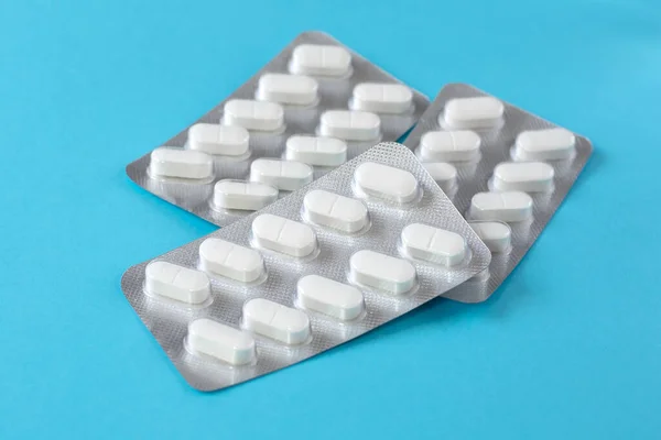 stock image Three blister packs with white tablets are on a blue background. The topic of pharmacology.