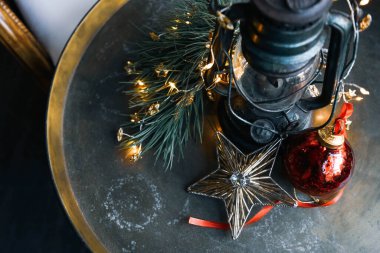 Antika bir lamba, camdan yapılmış bir yıldız ve diğer güzel Noel süsleri yuvarlak bakır bir masanın üzerinde. Retro tarzı. En üstten görüntüle.