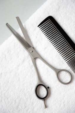 Filleting scissors and hairbrush are on the white terry towel. Copy space. View from the top point.