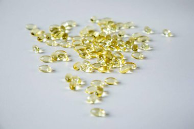 Şeffaf kapsüllerin D ya da Omega-3 vitaminli depozitosu gri bir arka plandadır.