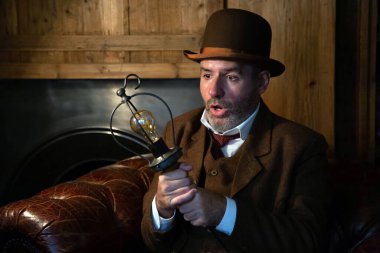 Viktorya dönemi şapkalı ve takım elbiseli bir adam elinde retro tarzı bir salonda bir ampulü görünce şaşırıyor. Teması geçen yüzyılın elektriği ve bilim tarihi..