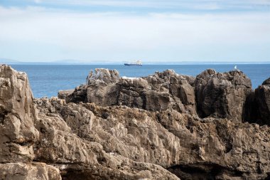 Mavi Atlantik Okyanusu 'nun arka planında kayalıklar ve bulanık odaklı bir gemi. Cascais, Portekiz.