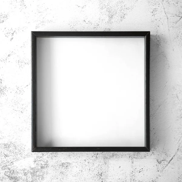 The black square frame is on a textured light background with gray splashes in the center of the image. View from the top. Square picture. Copy space.