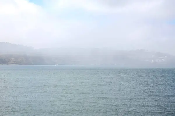 Sea landscape in fog. Sea water turquoise color and shore in fog. Lisbon, Portugal.