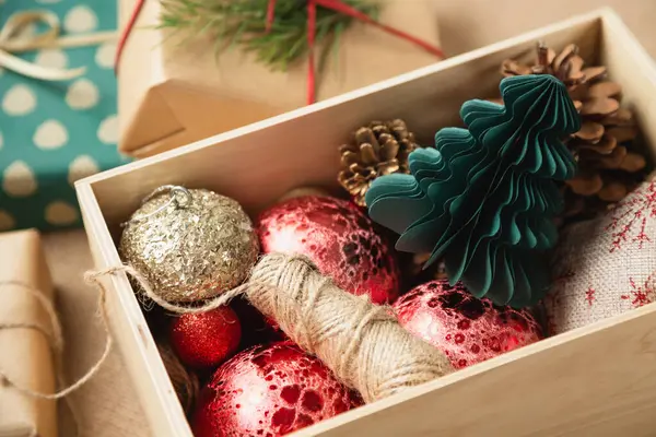 A paper tree and other decorations for Christmas and New Year are in a wooden box which is located on the table next to the wrapping gifts. Getting ready for Christmas.