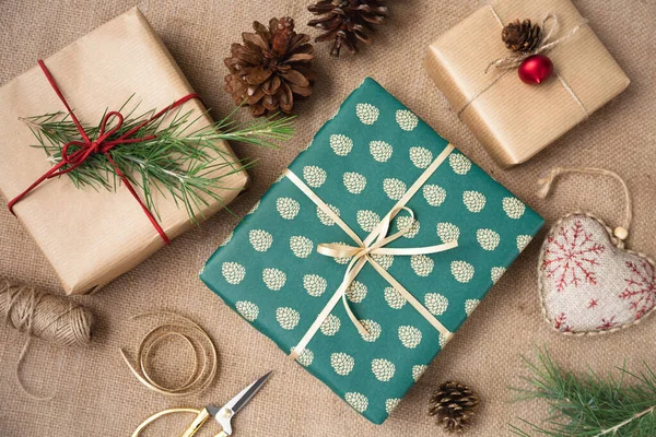Masanın üzerinde kağıt, ip, ladin konileri ve makas dolu hediyeler var. Noel için hazırlık. Yukarıdan görüntüle.