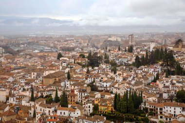 Tepenin tepesinden Granada şehri manzarası. Alhambra Sarayı nerede? Şehir manzarası bulutlu bir gökyüzüne karşı. Granada, İspanya.