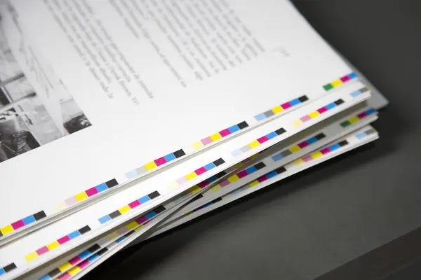 Kenarlarında yazı ve boya olan beyaz çarşaflar bir matbaada duruyor. Kağıt yapraklarının soyut bir arkaplanı.