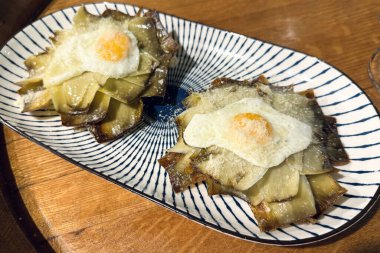 Tabağında yumurta olan iki pişmiş enginar ahşap bir masada..