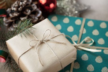 Zarif bir kağıda sarılmış, eski moda bir Noel süslemesiyle çevrili Noel hediyelerinin yakın çekimi..