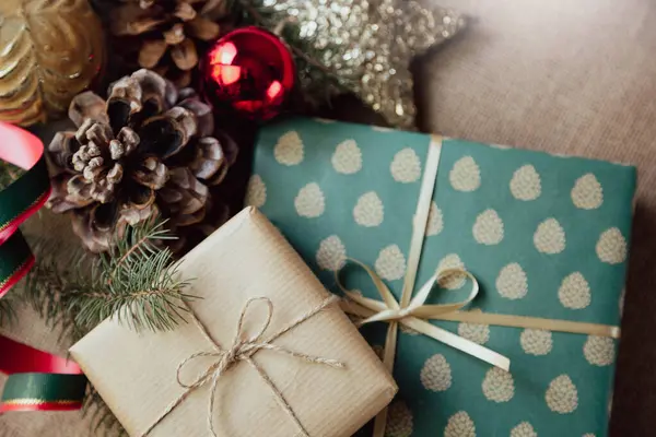 Zarif bir kağıda sarılmış, eski moda bir Noel süslemesiyle çevrili Noel hediyelerinin yakın çekimi..