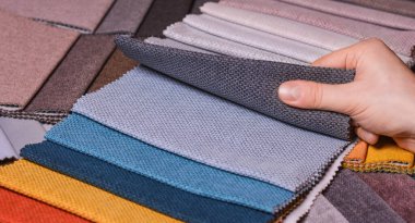 The customer looks at and selects the color fabric she likes, selects the fabric from the fabric swatches for her new sofa. clipart