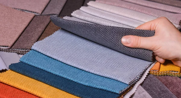 Stock image The customer looks at and selects the color fabric she likes, selects the fabric from the fabric swatches for her new sofa.