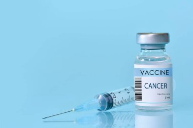 Mavi arka planda şırıngası olan bir şişedeki kanser aşısı. Kanser hastalıklarına karşı aşılama için deneysel kanser aşısı şişesi. Uzayı kopyala