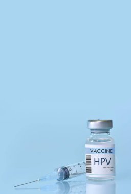 HIV Vaccine in a bottle with a syringe on a blue background. Experimental HIV vaccine vial for immunization against HIV disease. Copy space clipart