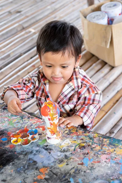 Asian toddler boy painting watercolor on plaster doll
