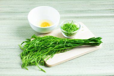 Akasya Pennata (Tırmanan gıdaklama) küçük cam kase ve tahta kesme tahtası üzerinde çiğ yumurta ile beyaz kase