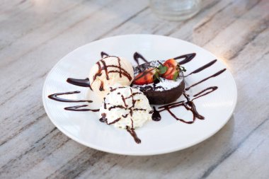 Beyaz tabakta dondurmalı siyah çikolatalı kek.