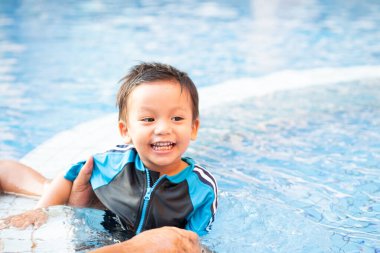 Küçük bir çocuk yüzme havuzunun kenarında oynuyor.