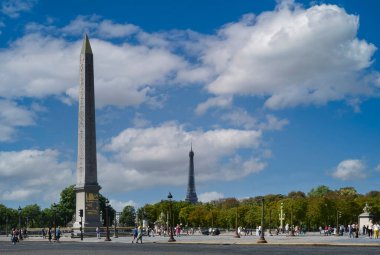 Paris 'teki Place de la Concorde manzarası Luxor' un dikilitaşı ve arka planda Eyfel Kulesi ile bir yaz günü mavi gökyüzü ve beyaz bulutlarla.