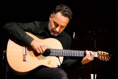 Portrait of Spanish musician and composer Jorge Drexler playing the guitar.