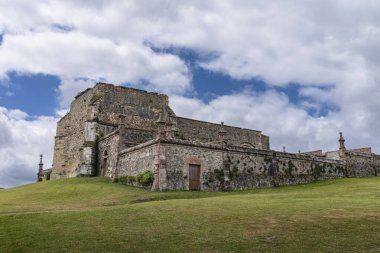 Cantabrian 'ın Comillas kasabasındaki Gotik mezarlığın kalıntıları, yeşil çayır ve bulutlu mavi gökyüzü..