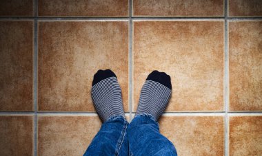 Görüntü 60 santimetre yukarıdan, fayanslı zeminde sıcak tonlarda çizgili çoraplar. Selfie konsepti.