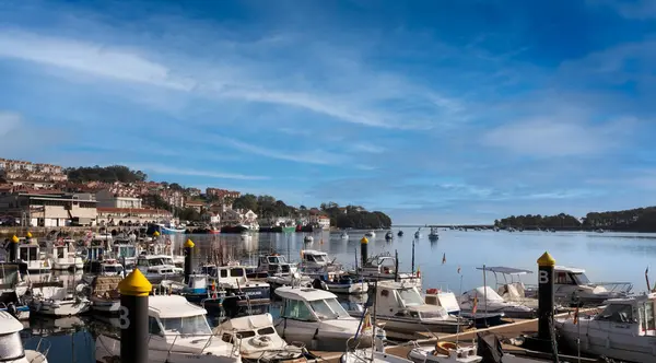 İspanya, Cantabria 'daki San Vicente de la Barquera körfezi manzarası. Zevk tekneleri ön planda ve mavi gökyüzü ve açık bulutlarla.
