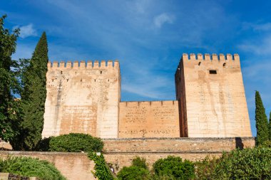 Granada 'daki Alhambra' nın dış duvar manzarası ve güçlendirilmiş kuleleri, gün ışığı ve mavi gökyüzü..