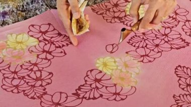 Tayland 'da kumaşa el yazması desenler çizerek batik yapmak.