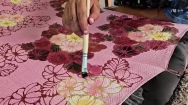 Tayland 'da kumaşa el yazması desenler çizerek batik yapmak.