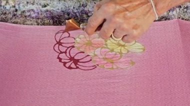 Tayland 'da kumaşa el yazması desenler çizerek batik yapmak.