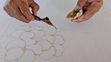 Tayland 'da kumaşa el yazması desenler çizerek batik yapmak.
